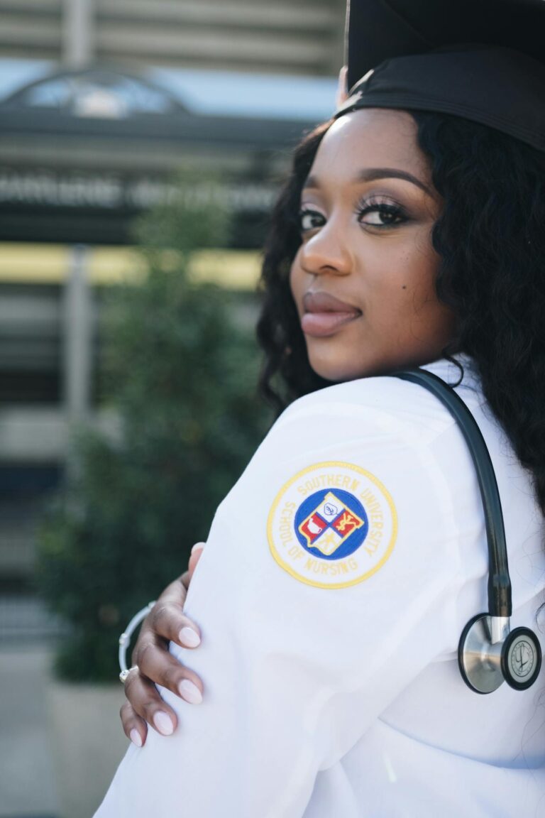 Confident nursing graduate posing outdoors in Baton Rouge with stethoscope and cap.